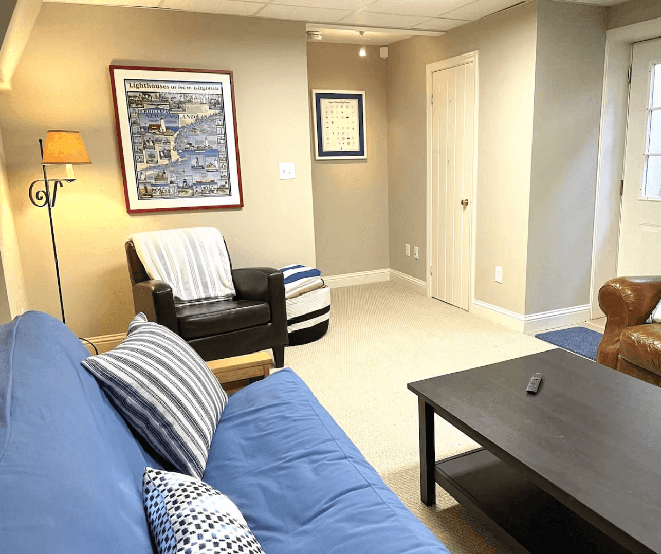 Finished basement lounge with a futon, leather chairs, and a New England lighthouses map